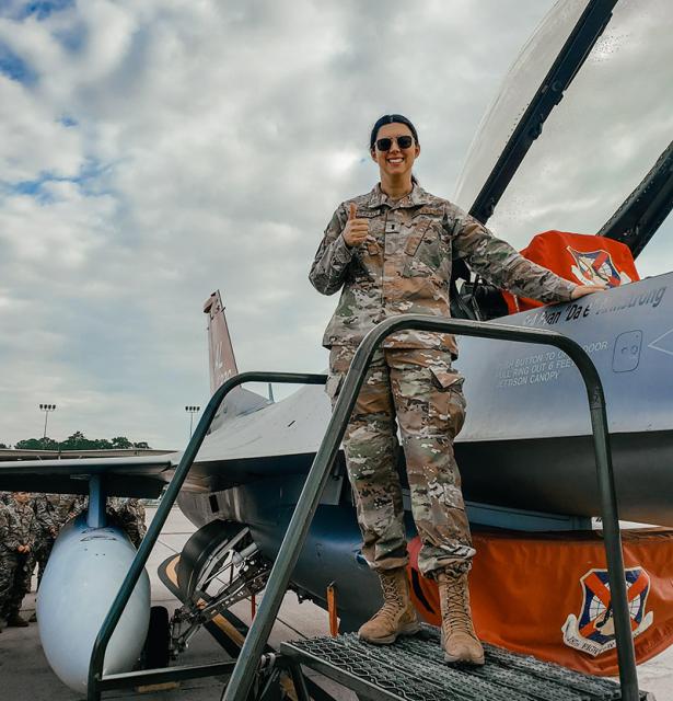 JAG Officer Carmen Flederbach in fatigues on wing of aircraft